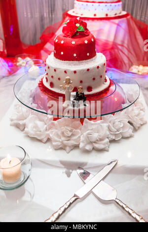 Figurine sul fondo del rosso e del bianco torta di nozze Foto Stock