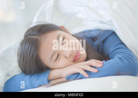Felice ragazza asiatica sdraiato sul letto con la luce del sole sul giorno pigro Foto Stock