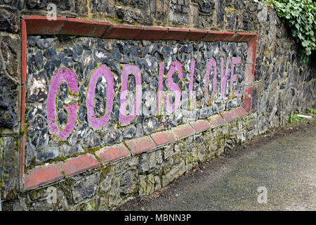 Chapel Street, Billericay, Essex, Inghilterra, aprile 2018, un muro di pietra che ha " Dio è amore " costruito in muratura e dipinte di rosso. Foto Stock