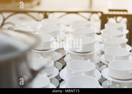 Coppe di zuppa e le piastre bianche sono messi sul tavolo per servita. Foto Stock