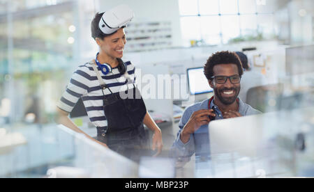 Sorridente programmatori di computer di programmazione realtà virtuale simulatore in ufficio Foto Stock