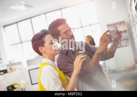 Focused creative business persone utilizzando la fotocamera del telefono in ufficio Foto Stock