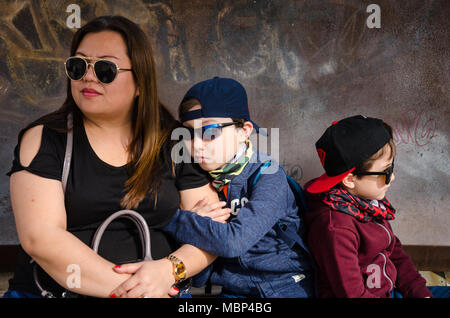 Una madre si siede e attende con i suoi due figli piccoli per un treno mentre è in vacanza in Spagna. Foto Stock