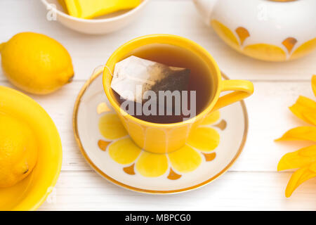 Giallo brillante, set da tè su un bianco tavola di legno Foto Stock