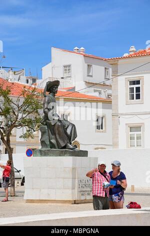 Una coppia in cerca di una mappa di fronte alla statua di Infante Dom Henrique (il principe Henry) in piazza con edifici del comune per la parte posteriore, Lagos, ALG Foto Stock