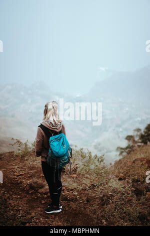 Escursionista femmina guardando verso il basso su una vertiginosa misty ridge sulla rotta per Coculi. Santo Antao Capo Verde Foto Stock