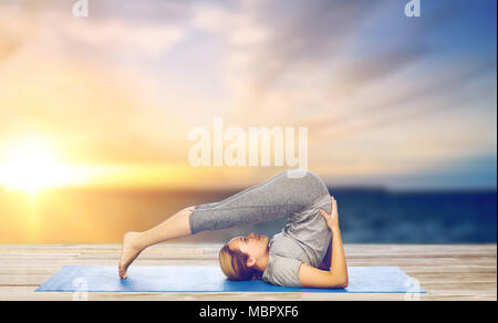 Donna fare yoga in aratro pone sul tappeto Foto Stock