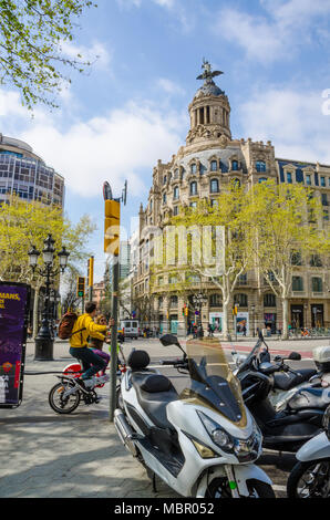 Una vista guardando attraverso il Passeig de Gracia di Barcellona, in Spagna in un edificio con una cupola e la figura sulla parte superiore. Foto Stock