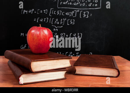 Apple su libri su una scrivania di legno durante le lezioni di matematica in classe Foto Stock