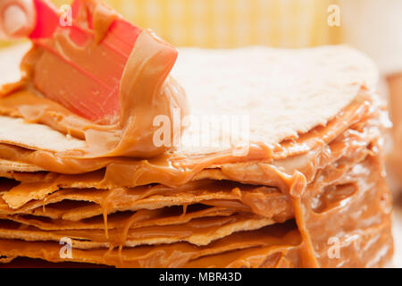 La donna lo strato di decorazione torta con dulce de leche in cucina Foto Stock