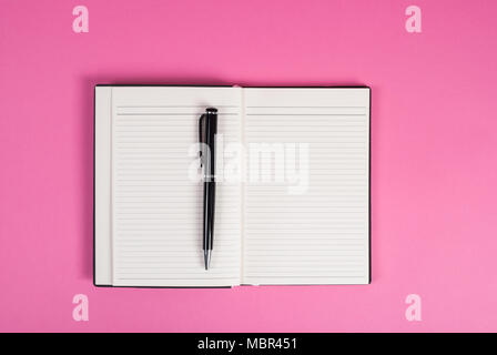 Note e penna vista superiore su un sfondo rosa Foto Stock