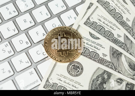 Nuovo denaro virtuale Golden bitcoin moneta e di dollari su una tastiera bianca. Cryptocurrency. Business e concetto di trading. Foto Stock