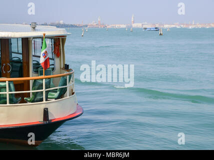 Bandiera dell'Italia sul primo piano della Laguna Veneziana con il centro storico di Venezia in background. Foto Stock