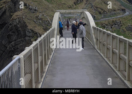 Turisti e fotografi attraversando il Mizen Head gorge sulla passerella pedonale che porta alla vecchia stazione di segnale e il faro e la punta di s/w Irlanda Foto Stock