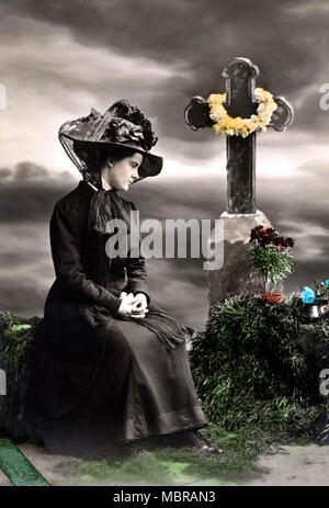 Vedova piange la morte di fronte a una grave sul cimitero, 1910s, Germania Foto Stock