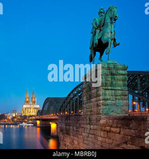 Statua equestre di Imperatore Guglielmo I. con la cattedrale di Colonia e il ponte di Hohenzollern nel blu ora, Colonia, nella Renania Foto Stock