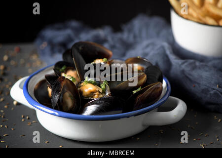 Moules-frites, le cozze e le patatine fritte tipiche del Belgio, su una tavola in legno rustico Foto Stock