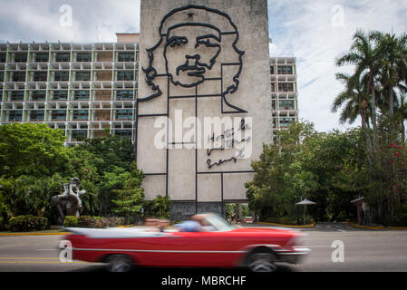 Classic American car drives davanti a un edificio con Che Guevara murale sul lato nella Piazza della Rivoluzione, l'Avana, Cuba. Foto Stock