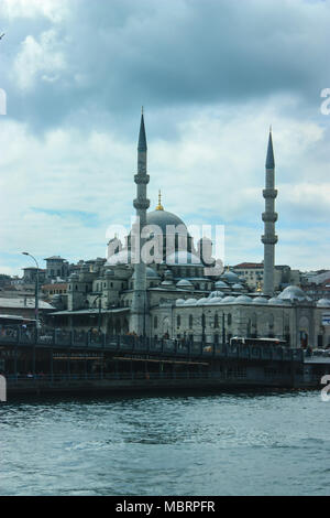 Bella Blu Yeni Kami moschea di Istanbul come visto da un traghetto con cielo nuvoloso e Istanbul city scape circostanti. Foto Stock