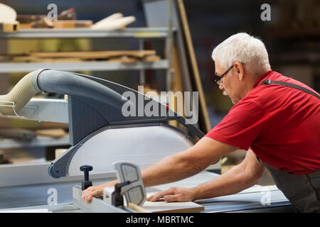 Carpenter con pannello visto e pannelli di fibre di legno in fabbrica Foto Stock