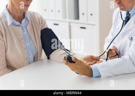 Medico con tonometro e senior donna all'ospedale Foto Stock