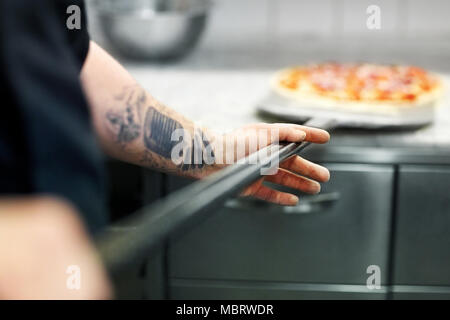 Cuocere o baker mano con pizza sul peel in pizzeria Foto Stock