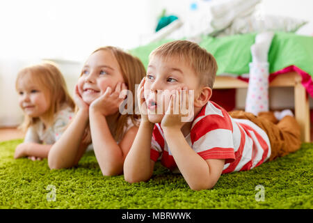 Felici i bambini sdraiato sul pavimento o tappeto Foto Stock