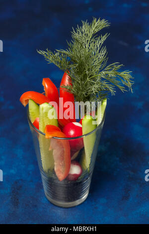 Un assortimento di verdure fresche in vetro - il peperone, il cetriolo e aneto su sfondo blu Foto Stock