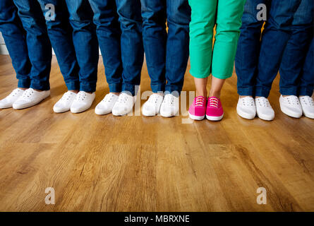 Donna in scarpe rosa in piedi in una fila di persone che indossano scarpe bianco Foto Stock