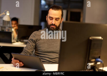 Uomo creativo con il computer lavora fino a tardi in ufficio Foto Stock