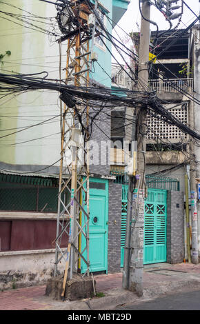 Elettrici e i cavi telefonici impigliato sui poli di potenza nella città di Ho Chi Minh, Vietnam. Foto Stock