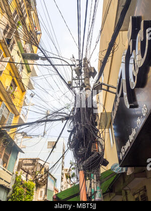 Elettrici e i cavi telefonici impigliato sui poli di potenza nella città di Ho Chi Minh, Vietnam. Foto Stock