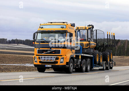 SALO, Finlandia - Aprile 6, 2018: Giallo Volvo FH semi trasporta Ponsse Elk forest spedizioniere sul rimorchio lungo l'autostrada su un nuvoloso giorno di primavera. Foto Stock