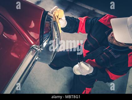 Uomini caucasici nella sua 30s che dettaglia il suo classico Auto con protezione corpo liquido. American veicolo da collezione. Profonda pulizia Automobile. Foto Stock
