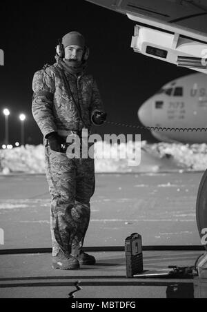 Senior Airman Garrett battaglia, 736th Manutenzione aeromobili squadrone di comunicazione e navigazione artigiano, sorge vicino al naso di un C-17A Globemaster III come il velivolo viene rifornito di combustibile, 5 gennaio 2018, alla Dover Air Force Base, Del. battaglia e altri 736th AMXS manutentori preparato il velivolo per una missione a temperature in basso gli adolescenti con un vento gelido oscillando attorno a meno tre gradi. (U.S. Air Force Foto di Roland Balik) Foto Stock