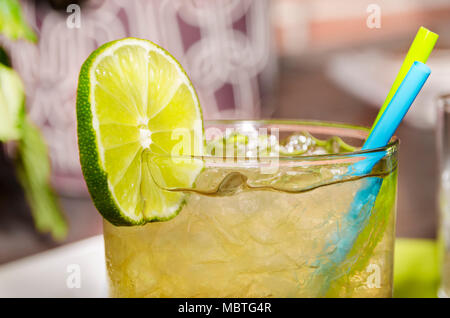 Bevanda ghiacciata con una fetta di limone in un bicchiere con due cannucce Foto Stock