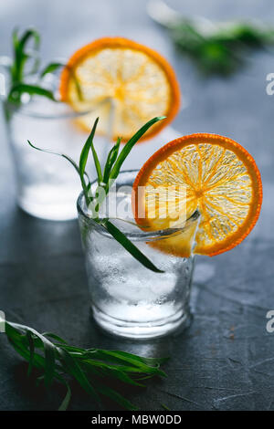 Due colpi di tequila cocktail con ghiaccio, essiccato fetta di arancia e di dragoncello fresco. Il concetto di un partito e di celebrazione. Foto Stock