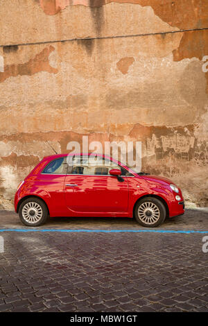Rosso Fiat 500 automobile parcheggiata su una strada acciottolata a Roma, Italia, la linea blu indica un è un pagare per parcheggiare bay con parchimetri nelle vicinanze dove potete acquistare Foto Stock