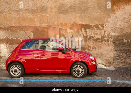 Rosso Fiat 500 automobile parcheggiata su una strada acciottolata a Roma, Italia, la linea blu indica un è un pagare per parcheggiare bay con parchimetri nelle vicinanze dove potete acquistare Foto Stock