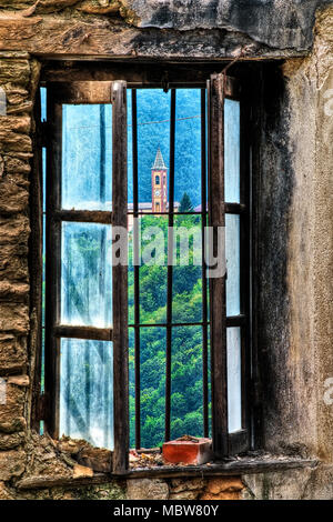 Il Cappello chiesa attraverso la finestra di una rovina abbandonati in Mindino, Garessio comune, Piemonte, Italia. Foto Stock