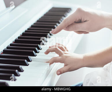 Primo piano immagine di due mani di madre e figlia suonare il pianoforte Foto Stock