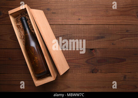 Lo Chardonnay vino Scatola: una sola bottiglia di vino Chardonnay in sua custodia in legno al buio su un tavolo di legno con copia spazio. Foto Stock