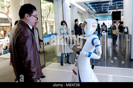 Shanghai, Cina. Xii Apr, 2018. Un cliente parla con un robot all'ingresso di un self-service area di Jiujiang Road ramo della China Construction Bank (CCB) a Shanghai in Cina orientale, Aprile 12, 2018. I clienti sono in grado di negoziare il 90 percento del denaro contante e non-cash business nel self-service area del ramo. Credito: Fang Zhe/Xinhua/Alamy Live News Foto Stock