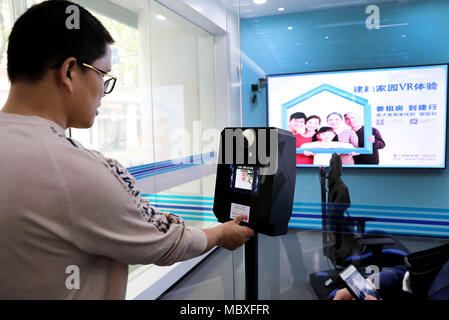 Shanghai, Cina. Xii Apr, 2018. Un cliente entra in un esperienza virtuale zona di un self-service area a Jiujiang Road ramo della China Construction Bank (CCB) a Shanghai in Cina orientale, Aprile 12, 2018. I clienti sono in grado di negoziare il 90 percento del denaro contante e non-cash business nel self-service area del ramo. Credito: Fang Zhe/Xinhua/Alamy Live News Foto Stock