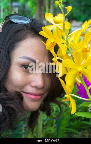 Ragazza Thai in posa presso la fattoria delle orchidee, Thon Buri, Bangkok, Thailandia Foto Stock