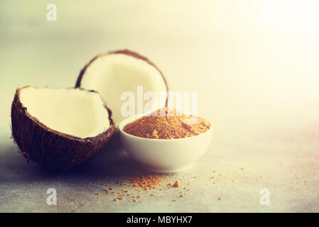 Palma da cocco di zucchero di canna e la metà dei frutti di noce di cocco sul cemento grigio Sfondo. Spazio di copia Foto Stock