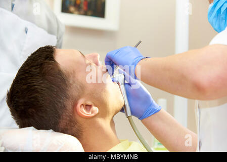 Le mani del dentista in blu guanti con attrezzature mediche in prossimità della bocca aperta del paziente. Foto Stock