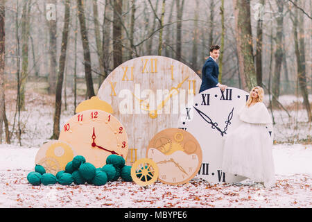 Happy sposi in posa a grandi orologi vintage in autunno foresta. Decorazioni Creative Foto Stock