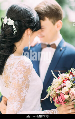 La vista del retro della sposa con il bouquet e abbracciando con lo sposo. Foto Stock