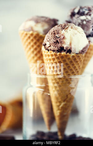 Cioccolato e caffè gelato in cono di cialda con i chicchi di caffè sulla pietra grigia sullo sfondo. In estate il concetto di cibo, copia dello spazio. Una sana senza glutine gelato. Banner Foto Stock